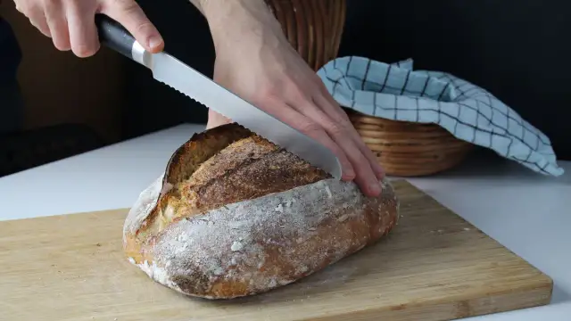 Krojenie świeżo upieczonego chleba na desce. Idealny przepis na chleb dla każdego.