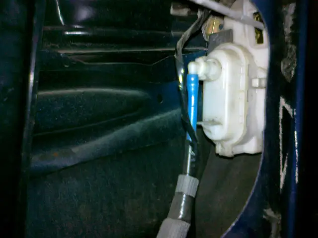 Mechanizm zamka w drzwiach VW Polo. Widoczny siłownik i przewody, pomocne przy pytaniu jak zamontować centralny zamek VW Polo.