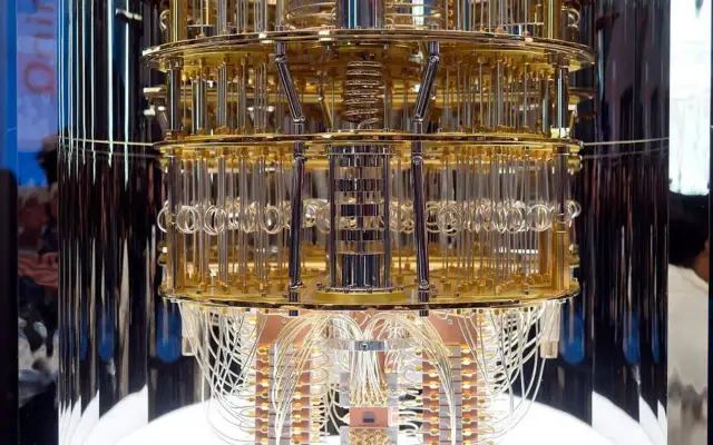 Złoty, wielopoziomowy komputer kwantowy z licznymi przewodami. Jego skomplikowana konstrukcja przypomina dzieło sztuki, a jego moc obliczeniowa może być porównywalna do szyfrowania AES 256.