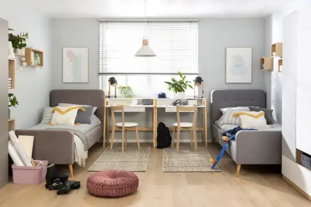 Jak podzielić pokój na dwa dla dzieci: dwa łóżka, biurka i półki tworzą funkcjonalne przestrzenie.