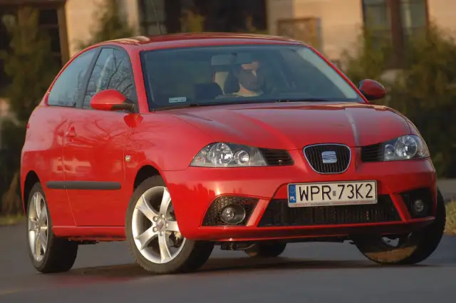 Czerwony Seat Ibiza 3, widok z przodu. Kierowca za kierownicą. Wymiary tego modelu są kompaktowe.