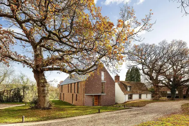 Nowoczesny dom z piaskowca obok starego dębu w jesiennej scenerii.