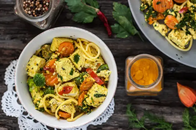Kolorowy makaron z tofu, brokułami i marchewką, doprawiony kurkumą. Pyszne i zdrowe danie.
