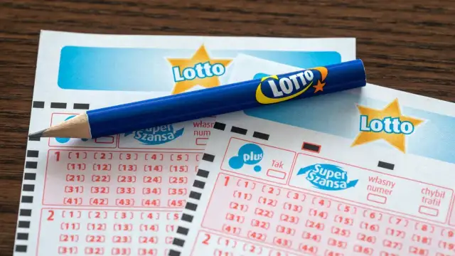 Niebieski ołówek na kuponach Lotto z zaznaczonymi polami do wyboru liczb.