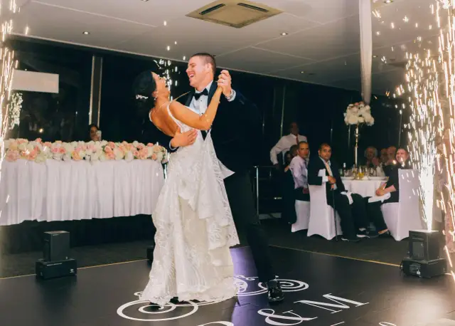 Para weselna tańczy na parkiecie, otoczona zimnymi ogniami.