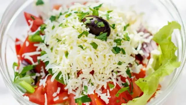 Sałatka szopska z tartym serem, pomidorami, ogórkiem, papryką, cebulą, oliwką i natką pietruszki.