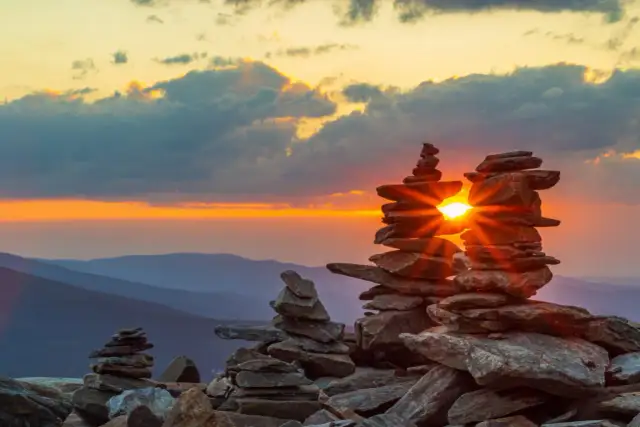 Zachód słońca w Sudetach, promienie przebijające się przez kamienne wieże.