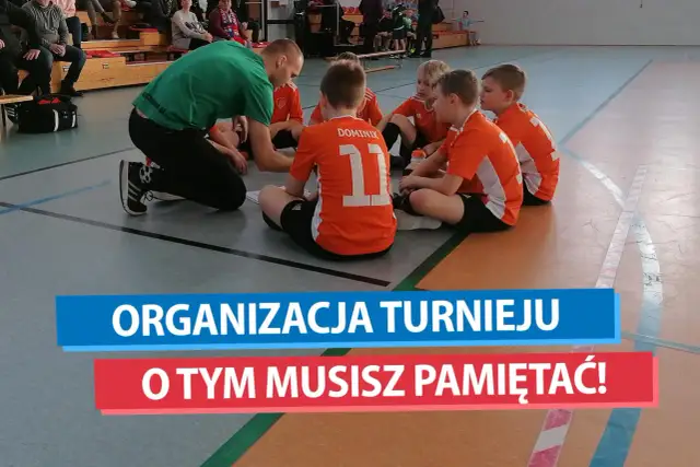 Trener w zielonej koszulce tłumaczy dzieciom w pomarańczowych strojach, jak zorganizować turniej piłki nożnej.