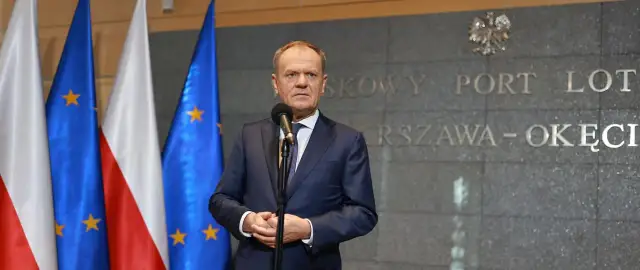 Premier Tusk, stojąc przed flagami Polski i UE, przemawia na tle napisu "Warszawa-Okęcie". Kto poparł zielony ład?