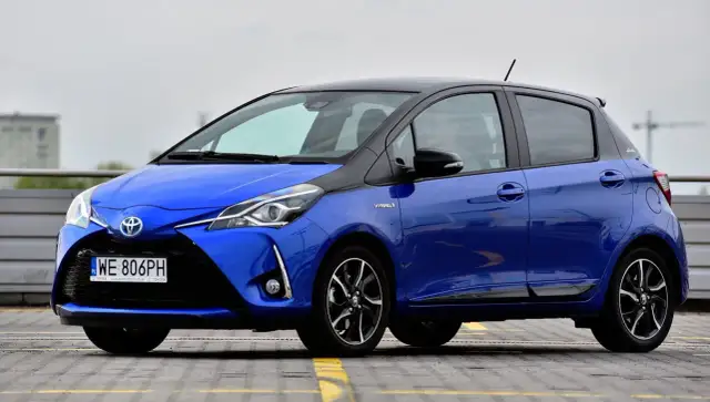 Niebieska Toyota Yaris Hybrid z czarnym dachem, zaparkowana na zewnątrz.