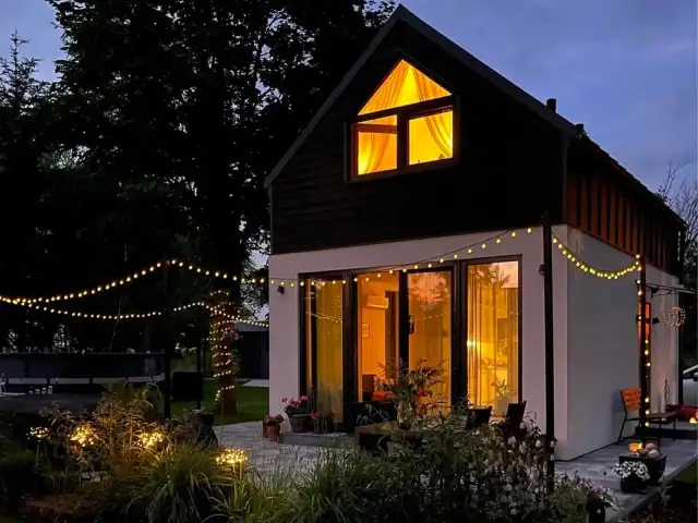 Przytulny dom modułowy oświetlony girlandami. Zastanawiasz się, ile kosztuje dom modułowy? Ten wygląda na wart swojej ceny.