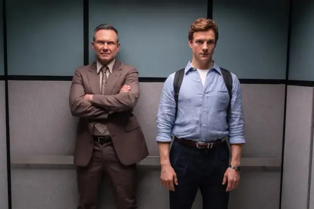 Dwóch mężczyzn w garniturach, jeden z nich to młody Dexter, który odkrywa swój **dexter original sin**.