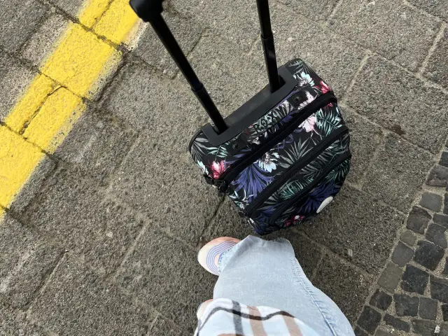 Podróżujesz z Ryanair? Jaki bagaż w cenie biletu? Mała, kwiecista walizka na kółkach czeka na lot.