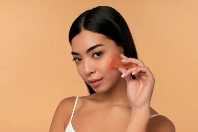 Kobieta wykonuje masaż twarzy bańką chińską, poprawiając kontur i wygląd skóry.