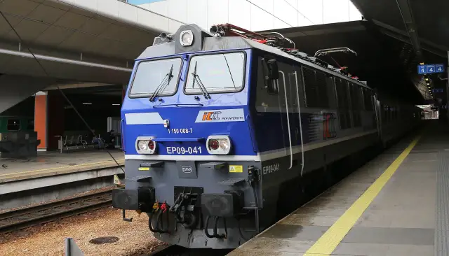Niebieski pociąg PKP Intercity EP09-041 stoi na stacji. Z którego peronu odjedzie pociąg? Tablica informacyjna wskazuje peron 4.