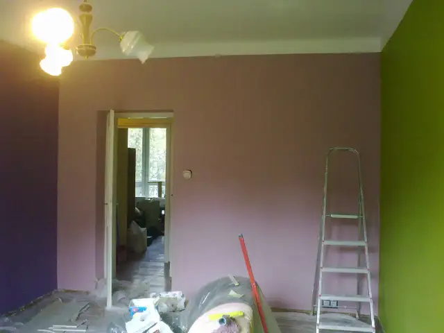 Fioletowa i zielona ściana, drabina i materiały malarskie. Zastanawiasz się, jak optycznie powiększyć pokój kolorami? Jasne barwy i kontrastujące akcenty mogą zdziałać cuda!