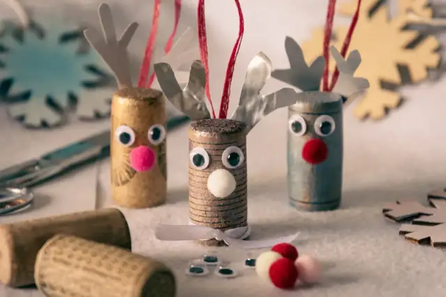 Trzy ozdoby świąteczne w kształcie reniferów z korków, z pomponami zamiast nosów i ruchomymi oczkami.