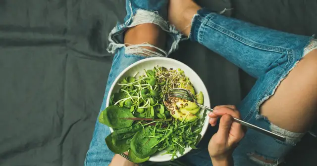 Osoba w podartych jeansach je sałatkę z kiełków, awokado i nasion. Czy to wszystko, czego brakuje w diecie wegetariańskiej?