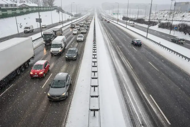 Autostrada A1 w zimowych warunkach, z samochodami i ciężarówkami na ośnieżonej nawierzchni.