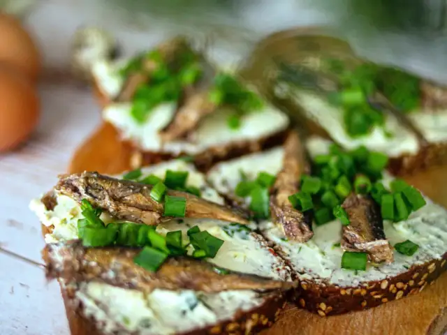 Kanapki z ciemnego pieczywa z pastą, sardynkami i szczypiorkiem.