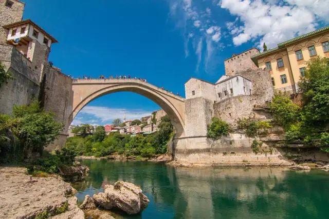 Mostar, Bośnia i Hercegowina. Słynny Stary Most nad rzeką Neretwą. Turyści podziwiają widoki, a ceny pamiątek są przystępne.