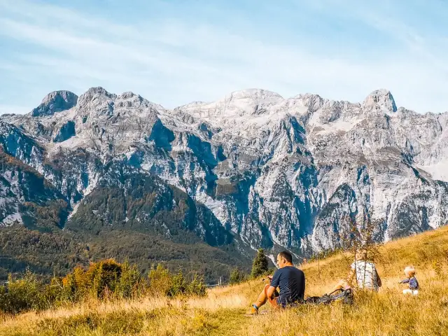 Rodzina odpoczywa na trawiastym zboczu, podziwiając majestatyczne albania góry.