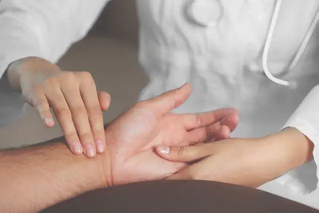 Lekarz bada puls pacjenta na nadgarstku.