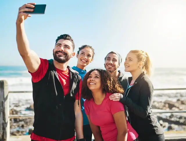 Grupa przyjaciół robi sobie selfie nad morzem. Ich uśmiechy to najlepsze cytaty o sobie, pełne radości i wspólnych chwil.