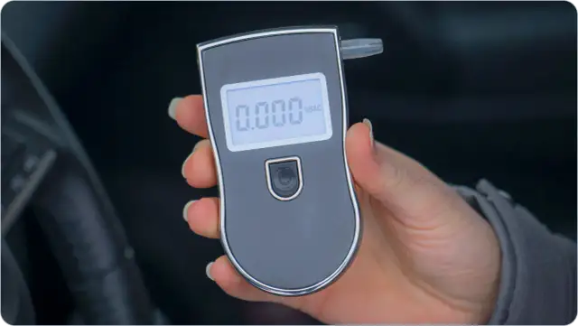 Dłoń trzyma alkomat z wyświetlaczem pokazującym 0.000.