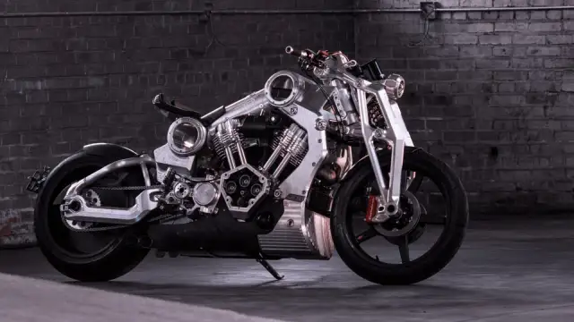 Wyjątkowy, lśniący motocykl, prawdopodobnie najdroższy motor na świecie, z masywnym silnikiem i detalami z polerowanego metalu, na tle ceglanej ściany.