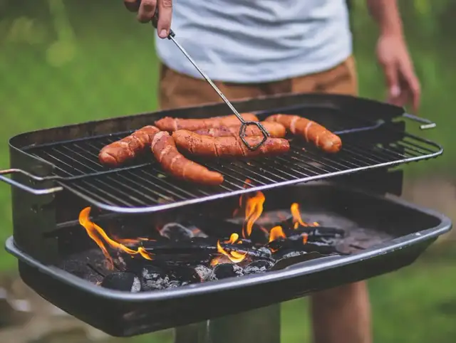 Kiełbaski skwierczą na grillu, idealne miejsce, gdzie zrobić grilla w ogrodzie.