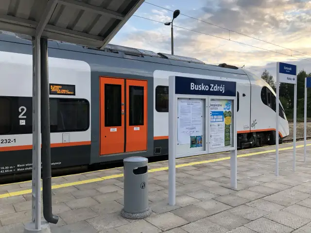 Pociąg do Buska Zdroju na peronie. Tablica informacyjna z nazwą stacji i rozkładem jazdy. Jak dojechać pociągiem do Buska Zdroju? Tu znajdziesz odpowiedź.