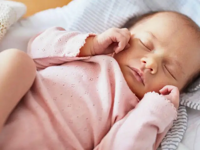 Śpiące niemowlę w różowym ubranku.