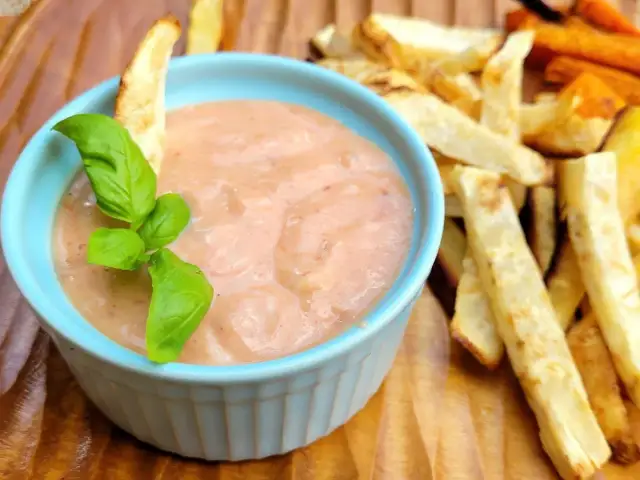 Pikantny sos w niebieskiej miseczce, idealny jako dodatek do pieczonych frytek ziemniaczanych i marchewkowych. Co pasuje do frytek? Ten sos!