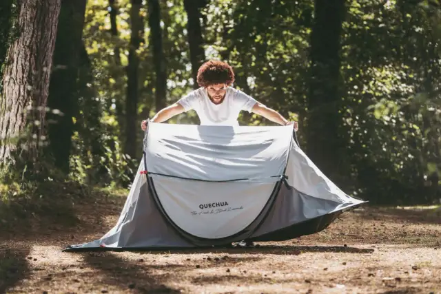 Mężczyzna rozkłada namiot samorozkładający Quechua w lesie. Proste jak złożenie namiotu samorozkładającego.