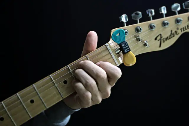 Dłoń grająca akord na gryfie gitary Fender Telecaster z kostkami.