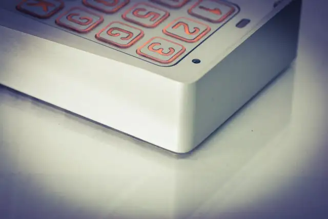 Zbliżenie na klawiaturę domofonu z podświetlanymi na pomarańczowo przyciskami.