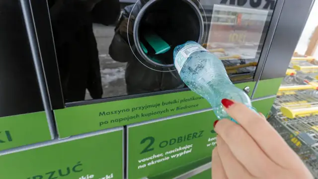 Kobieta wrzuca plastikową butelkę do maszyny przyjmującej opakowania.