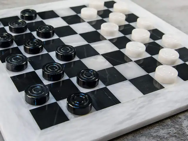 Plansza do gry w warcaby z czarnymi i białymi pionkami.