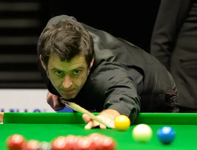 Ronnie O'Sullivan w akcji, skupiony na grze w snookera. Jego sportowa pasja widoczna w każdym ruchu.