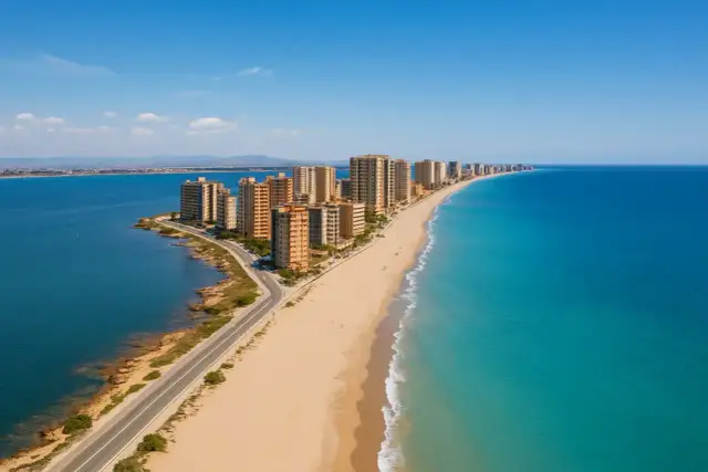 Hohe Gebäude säumen eine lange Sandbucht mit türkisfarbenem Meer und blauer Lagune.