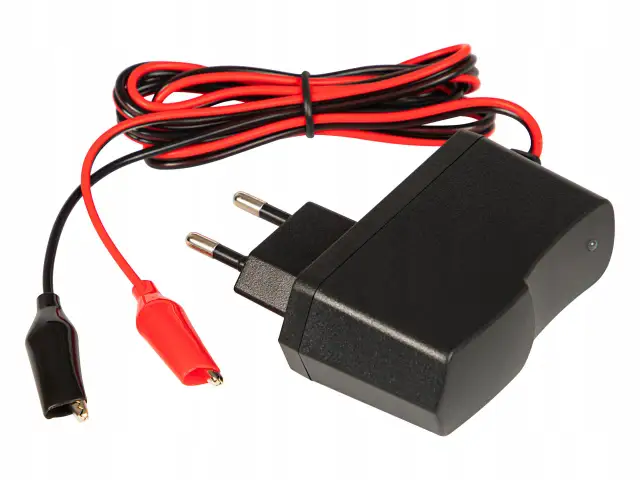 Prostownik do akumulatorów z czarnymi i czerwonymi przewodami oraz krokodylkami.