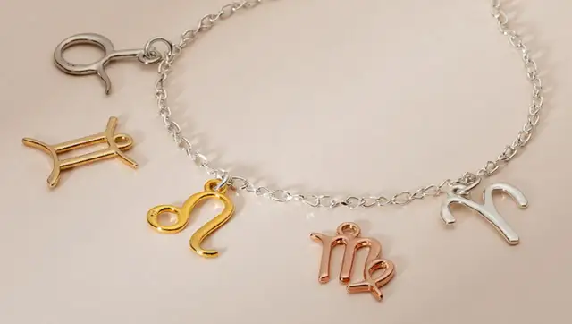 Bransoletka z zawieszkami w kształcie znaków zodiaku. Niektóre zawieszki mają piękne kolory złota, inne są srebrne lub w odcieniu różowego złota.