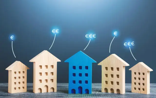 Drewniane domki symbolizują inwestycje, a symbole euro wskazują na zyski. To wizualizacja udanego repair, czyli naprawy finansów poprzez nieruchomości.