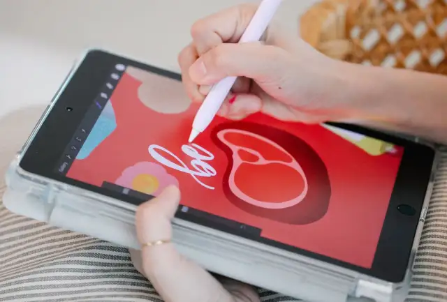 Rysowanie na tablecie za pomocą rysika w aplikacji do rysowania. Na ekranie widać czerwone tło z grafiką steka i kwiatka.