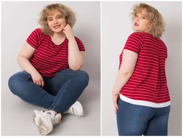 Kobieta plus size w czerwonej bluzce w paski i jeansach siedzi na podłodze.