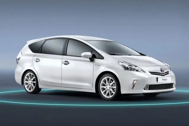 Biały Toyota Prius+ na tle niebieskim. To auto hybrydowe, które oferuje przestronne wnętrze, idealne dla rodziny. Ile miejsc ma ten model?