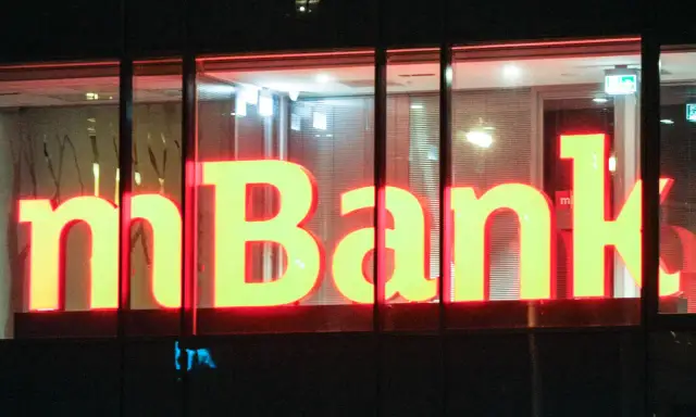 Jasne, oto propozycja tekstu alternatywnego:

Neonowy napis "mBank" świeci w nocy. To bank, do którego należą miliony Polaków, oferujący nowoczesne usługi finansowe.