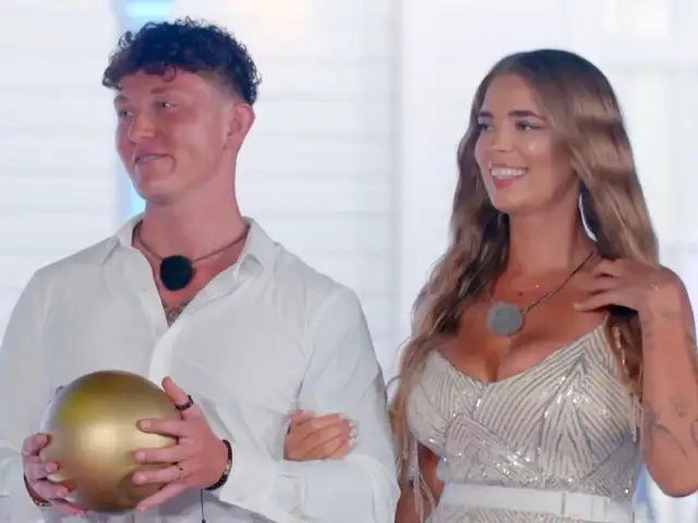 Para z Hotel Paradise 7, on trzyma złotą kulę, ona w błyszczącej sukience.