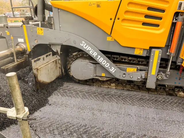 Asfaltarka w akcji, układająca nawierzchnię drogową.